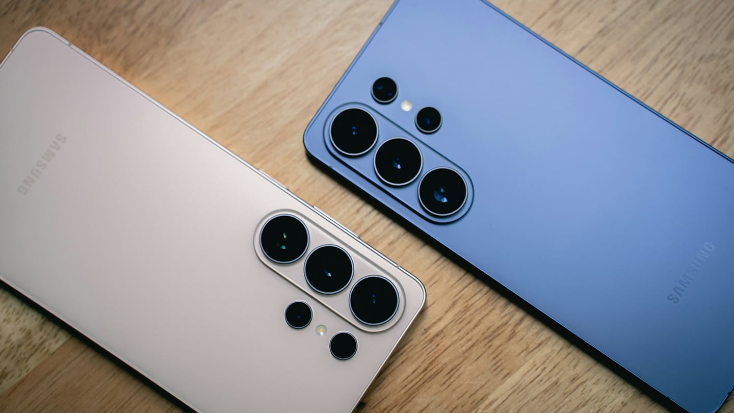 Samsung Galaxy S26 Ultra 粉金色與藍色機身背面並排放在木桌上,清楚呈現多鏡頭相機模組與霧面背蓋設計。
