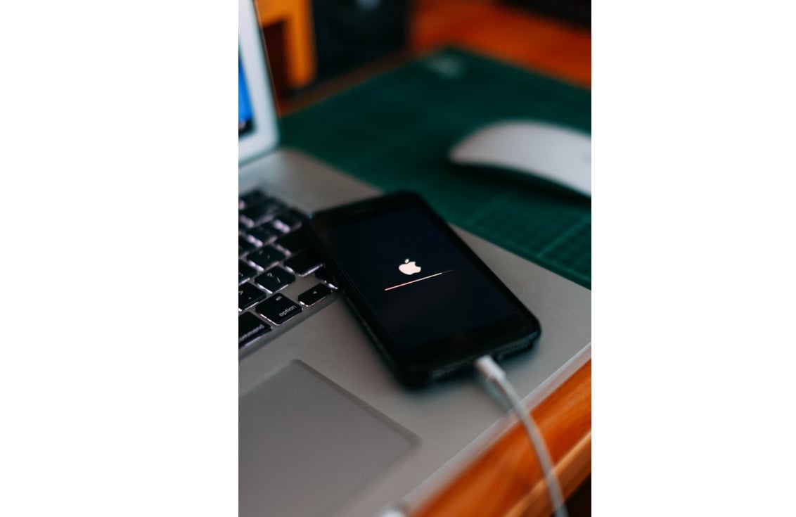 一部 iPhone 螢幕中心顯示經典 Apple LOGO 圖示。